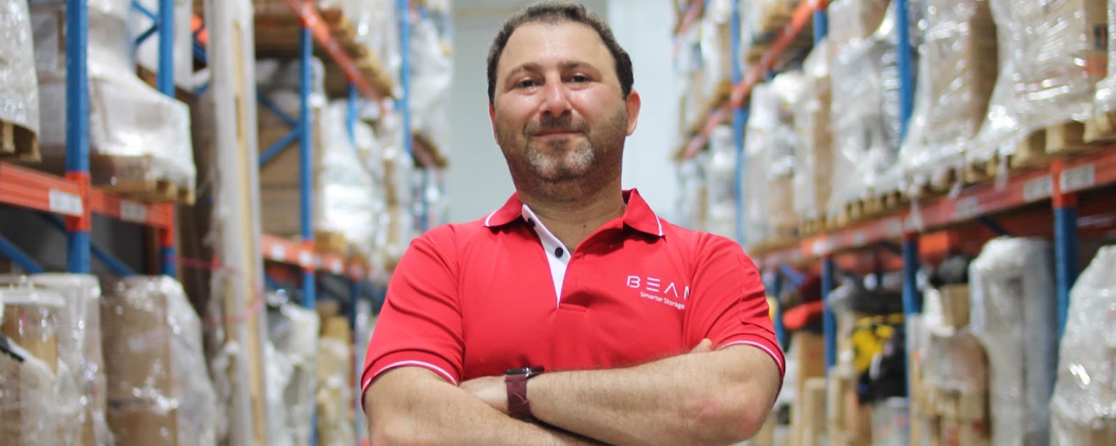 A smiling BEAM Space employee in front of a facility