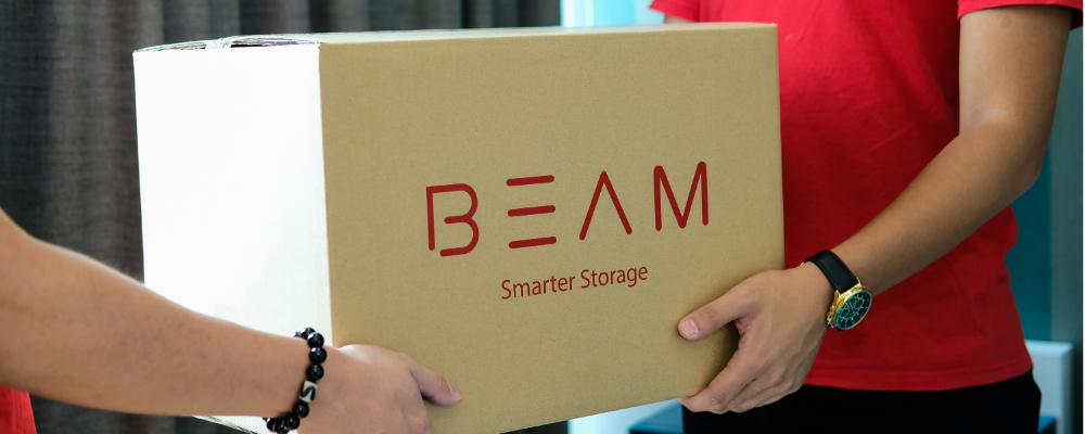 A BEAM Space Crew member collecting a boxed item from a customer, containing sports equipment.